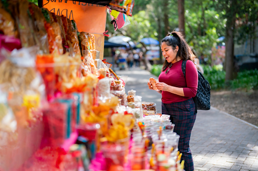 Latin woman tourist holding traditional Mexican sweet candies while standing on street market