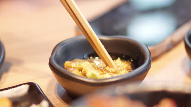 Human hand use chopsticks to mix the shoyu and garlic.
