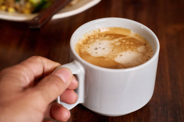 hand holding a cup of  coffee on dining table