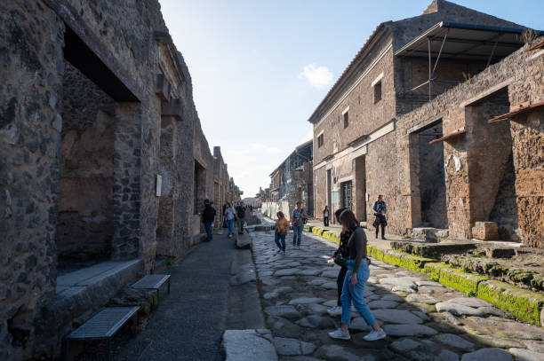 People walking through the Ancient Pompeii (UNESCO World Heritage Site). Paving stones of Via del Foro in November 2023. Pompeii, Italy : 2023 November 16 : People walking through the Ancient Pompeii (UNESCO World Heritage Site). Paving stones of Via del Foro in November 2023. victims the ruins of pompeii stock pictures, royalty-free photos & images