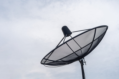 A Black Satellite dish on roof for TV channe in blue sky with cloudy Background