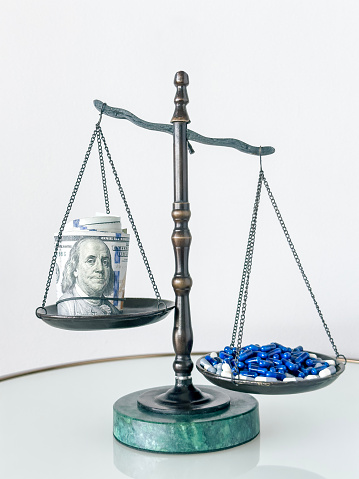 Still life of a scale of justice with roll of dollar bills and a pile of pills
