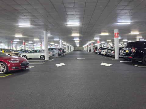 The shined underground garage with the moving cars and parked cars.
