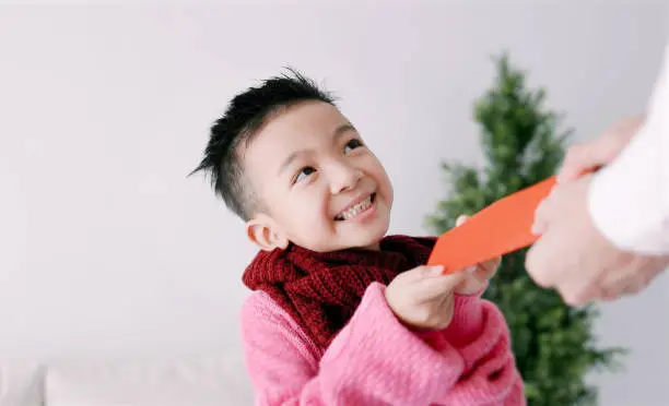 happy asian little boy receiving red envelope and celebrating chinese new year
