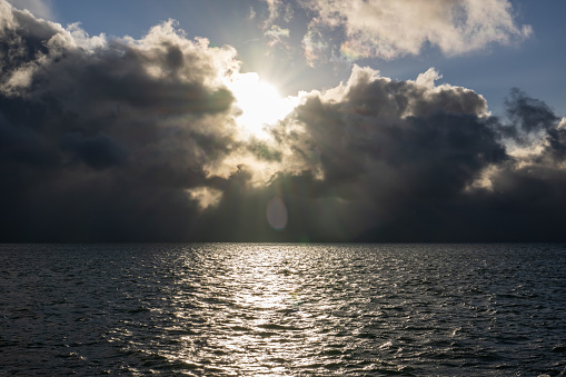 sunset over the sea with sun rays and dark clouds