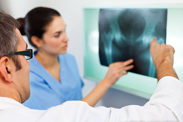 médico, olhando para a radiografia da imagem da pélvis - x ray image radiologist examining using voice imagens e fotografias de stock