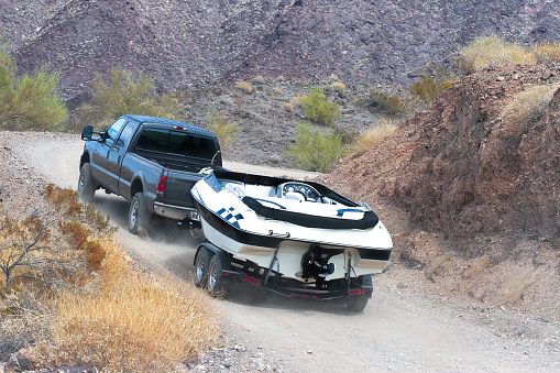 A car towing a boat through the dirt road