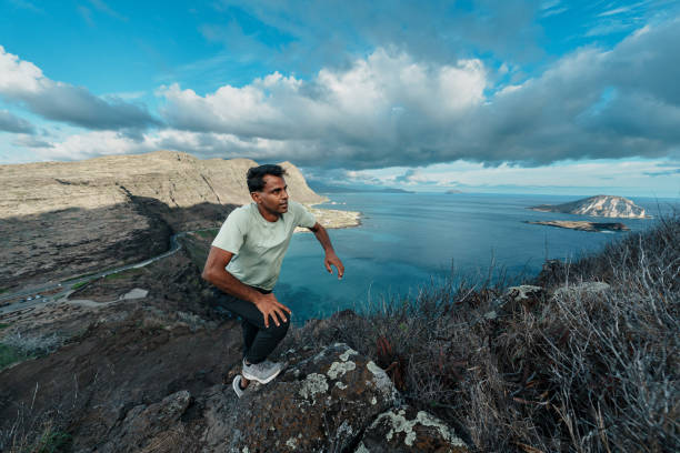 istock Man climbs rocky peak overlooking ocean 1854051699