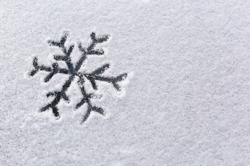 Snowflake painted on a snowy background. Black snowflake on a white background. Drawing in the snow.