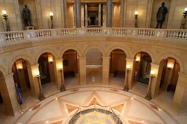The Minnesota Capitol building interior, featuring the rotunda balcony under the circular dome area. The architecture houses the State Senate, House of Representatives, Attorney General, the office of the Governor, and the Supreme Court of Minnesota
