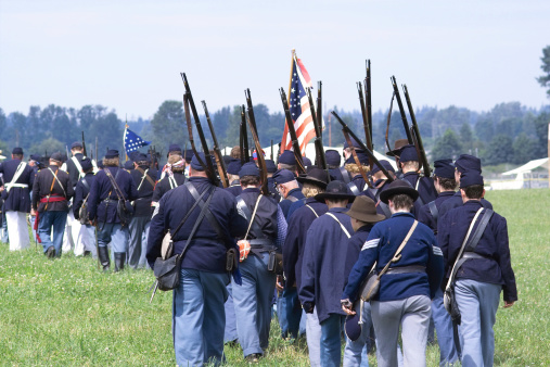 Soldiers walking across a battle field as part of an American Civil War reenactment.