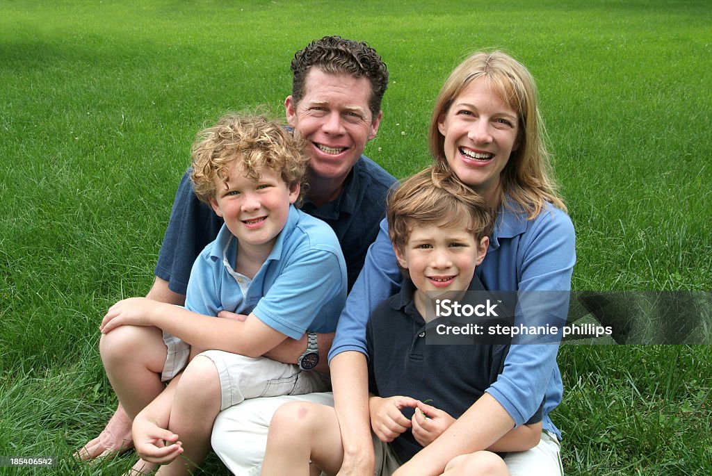 Famiglia di quattro seduti all'aperto su una bella giornata d'estate - Foto stock royalty-free di Adulto
