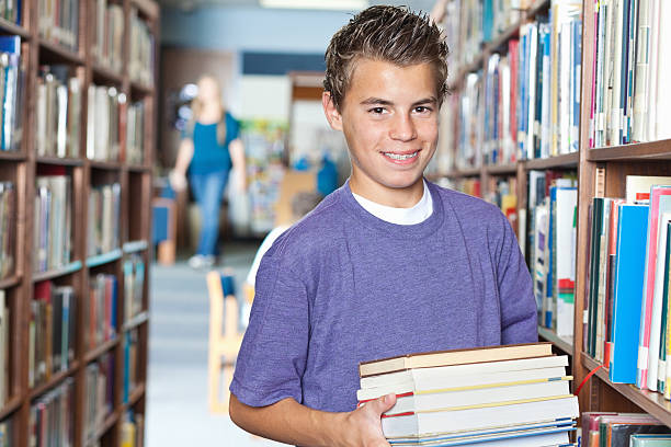 istock Young student holding books in school library, with copy space 185407417