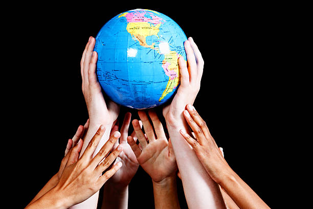 istock Many hands cradle the globe against black 185408374