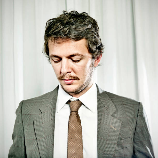 This close-up shot of a grim, frowning, furious businessman with jaw clenched glaring at something is distorted by the use of a fisheye lens.