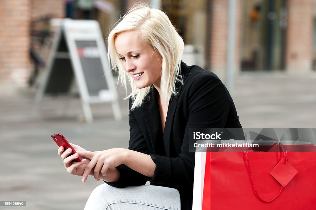 Mulher na viagem de compras textos em seu telefone - Foto de stock de 20 Anos royalty-free