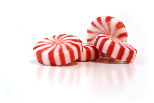 Four peppermint candies isolated on a white reflective background.  Studio set-up.