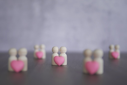 Wooden dolls and pink heart with copy space. Love, romantic, relationship, couple concept