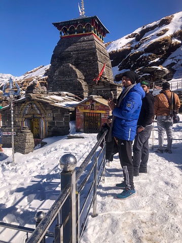 uttarakhand, India – December 12, 2023: An adult male is pictured standing in front of a majestic temple entrance, looking pensively in awe at the impressive architecture