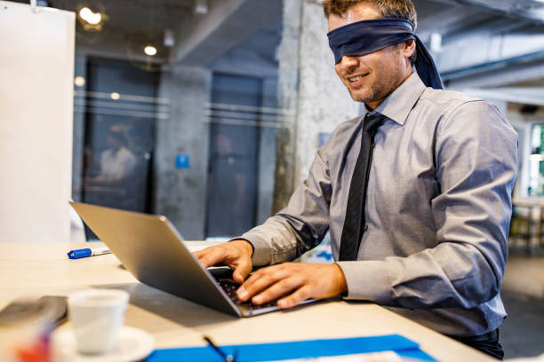 istock Blindfolded businessman unable to see the reality over computer in the office. 1854174777