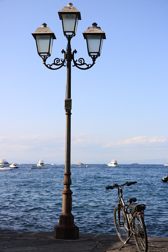 Nineteenth-century street lamp and parked bicycle. In the background the blue sea.