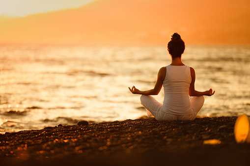 Woman relaxingly practicing meditation in the pine forest to attain happiness from inner peace wisdom with beam of sun light for healthy mind and soul for healthy mind and soul