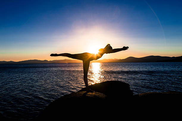 Young woman doing yoga at sunset on Lake Tahoe stock photo
