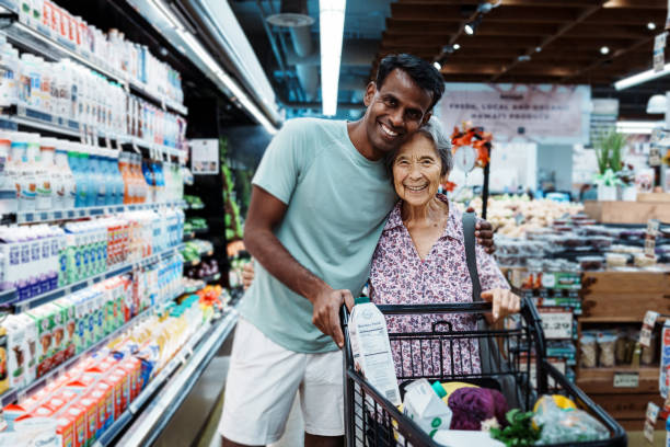 istock Elderly woman greets friend with hug while grocery shopping 1854218123