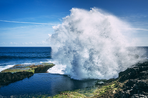 half underwater shot of surfer surfing a reef break wave in Indonesia