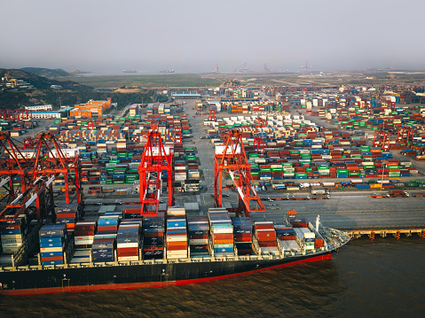 Horizontal wide angle view of heavy loaded container cargo ship in busy strait of Malacca.