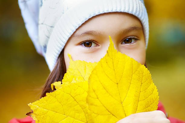 portrait of a beautiful teenage girl with yellow leaves in autumn