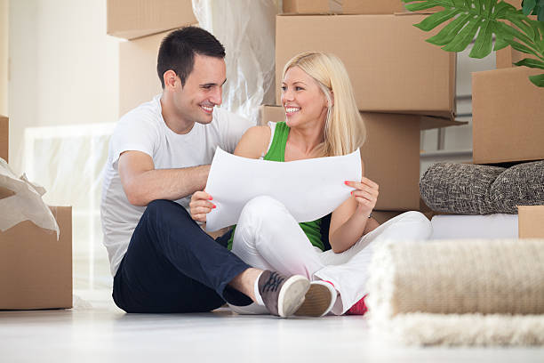 istock couple sitting on floor looking at house plans 185427084
