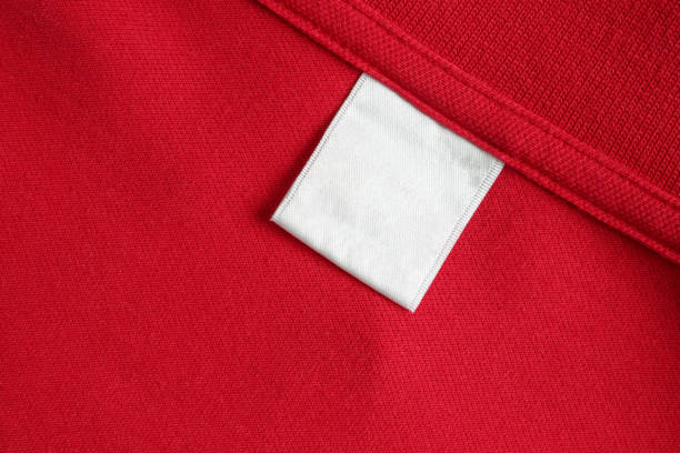 istock Blank white laundry care clothes label on red shirt fabric texture background 1854276619