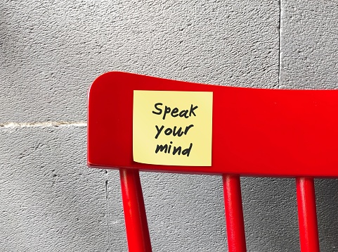 Red chair with stick note written SPEAK YOUR MIND, self reminder to have self respect, not afraid to have strong opinions and show ideas how to improve things