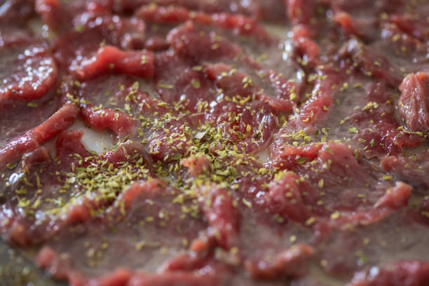 Sliced beef on plate,  seasoned with salt, lemon juice, olive oil and oregano, close up, Carpaccio