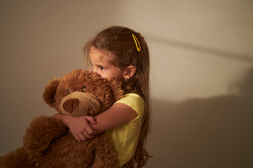 Beautiful girl hugging her Teddy bear, being sad