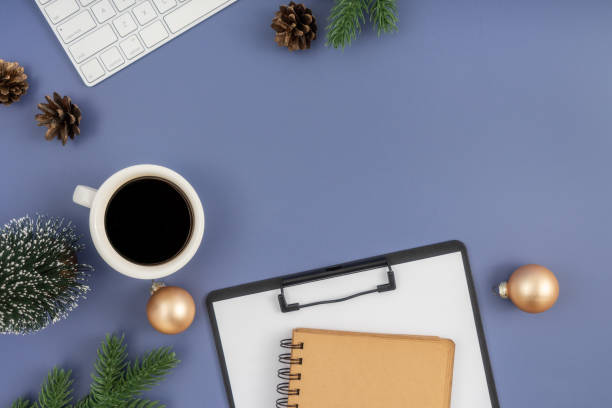istock Christmas concept. Computer Keyboard, Clipboard, notepad, cup of coffee and christmas decoration on pastel blue background. 1854304565