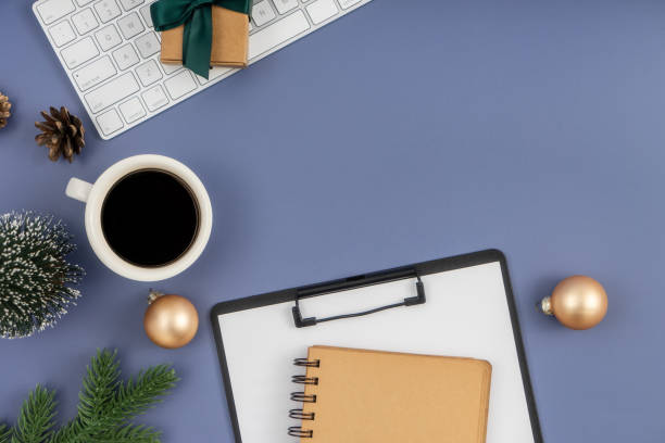 istock Christmas concept. Computer Keyboard, Clipboard, notepad, cup of coffee and christmas decoration on pastel blue background. 1854304733