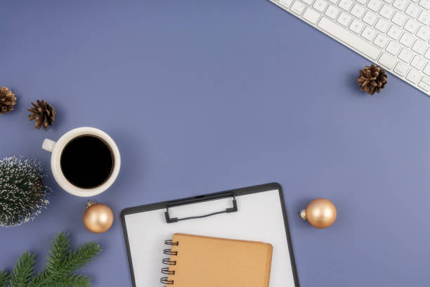 istock Christmas concept. Computer Keyboard, Clipboard, notepad, cup of coffee and christmas decoration on pastel blue background. 1854305120