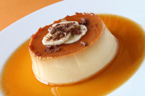 A banana creme caramel decorated with banana slices and chocolate shavings.