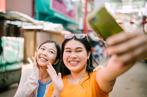 Two beautiful young asian woman taking selfie together while travelling. Gen Z lifestyle.