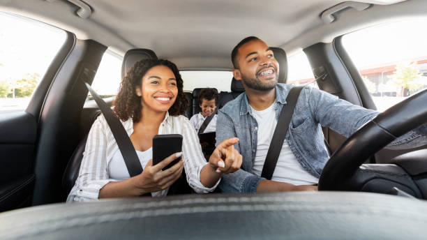 Positive black family have car ride, using smartphone for navigation