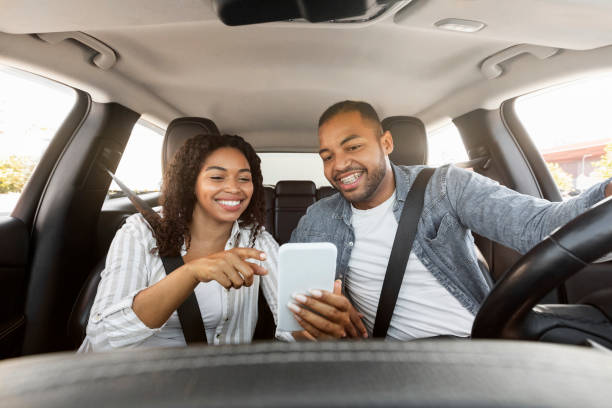 istock Happy black couple having car trip together, using cell phone 1854346040