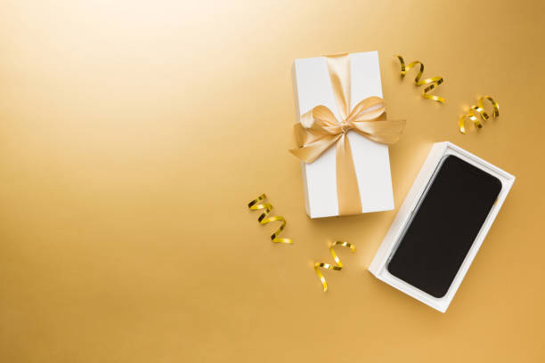 istock Opened gift box with gold ribbon and smartphone on color background, top view. Blank open box packaging mockup , Template for your design - branding mockup 1854359232