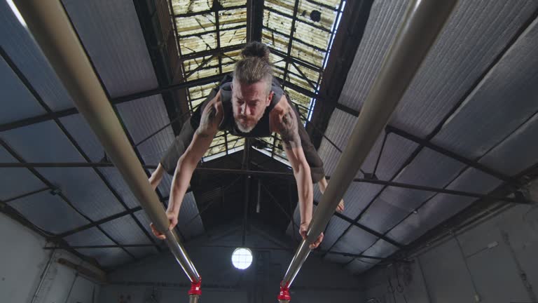 Strong Gymnast Holding Handstand on Parallel Bars in Training Gym