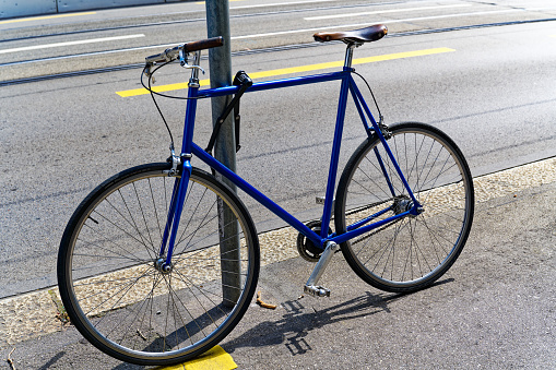 Blue old style one gear bicycle with leather saddle secured at metal pole at City of Zürich on sunny and hot summer day. Photo taken July 20th, 2023, Zurich, Switzerland.