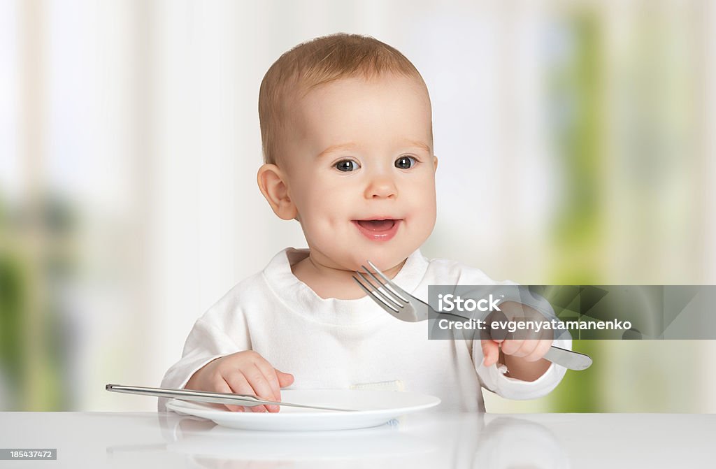 Funny baby con un cuchillo y tenedor comer alimentos - Foto de stock de Alegre libre de derechos