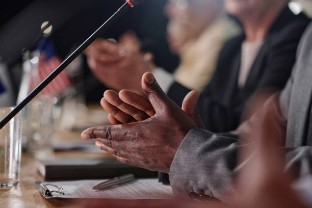 Selective focus shot of diverse group of business people sitting at conference table and applauding after a successful project meeting.