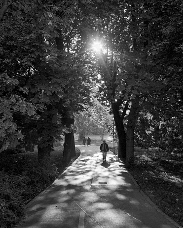 Augsburg, Germany - March 02, 1989: Pedestrians walking on a shady pathway in Augsburg, Germany. Film scan