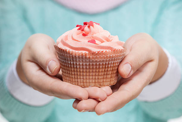 istock Woman holding a pink cupcake on white 185439833